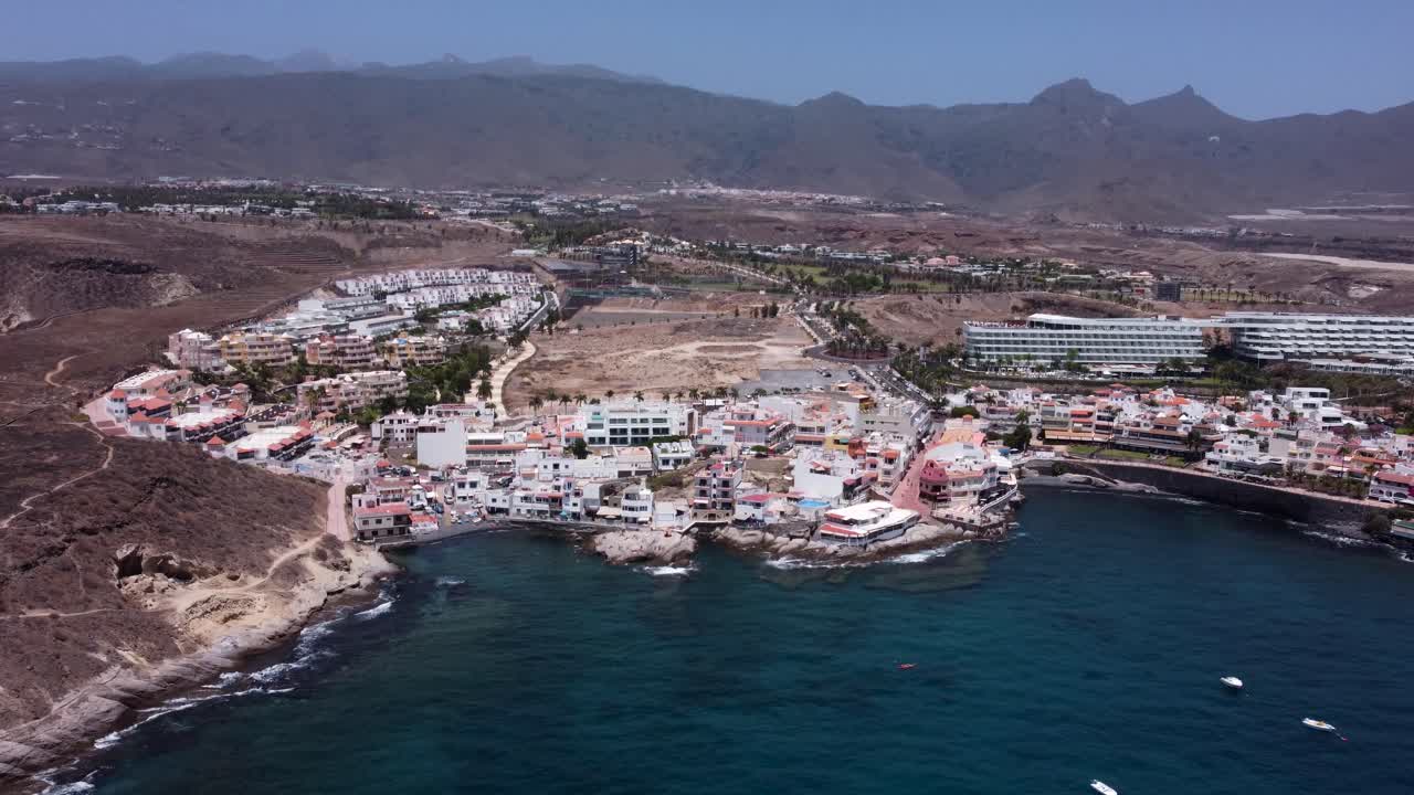 Drone view of small village by the ocean with mountains in the background in La Caleta, Tenerife, Canary Islands, Spain.
