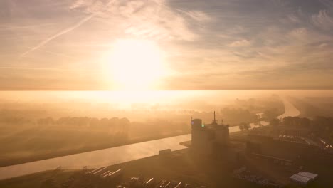 sunrise over foggy canal and industrial area