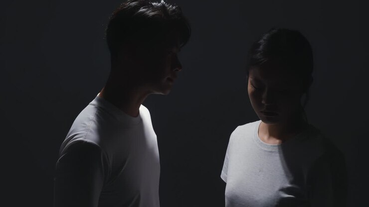 Concetto di donna vittima di violenza. Giovane donna stressata e depressa che piange tristemente, coprendosi il viso a causa della violenza domestica; stato depressivo, problemi di salute mentale e concetto di emozioni negative.