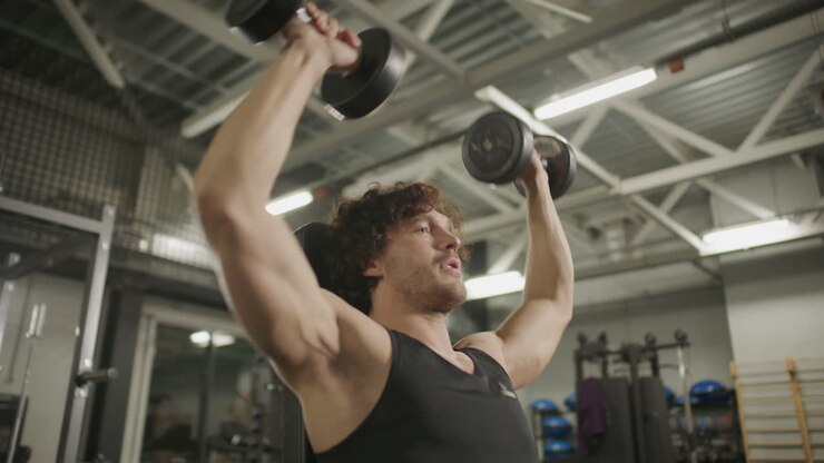 Young Man Performing Seated Overhead Press with Dumbbells in Gym