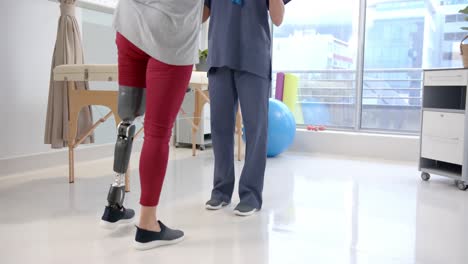 caucasian female physiotherapist and female senior patient with prosthetic leg exercising