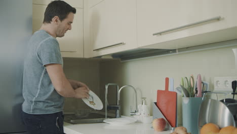 Husband-doing-household-chores-after-dinner.-Man-washing-dishes-with-sponge