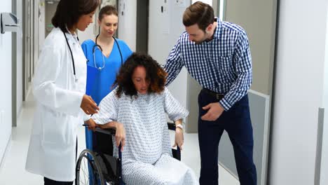 man and doctors assisting pregnant woman to sit on wheelchair