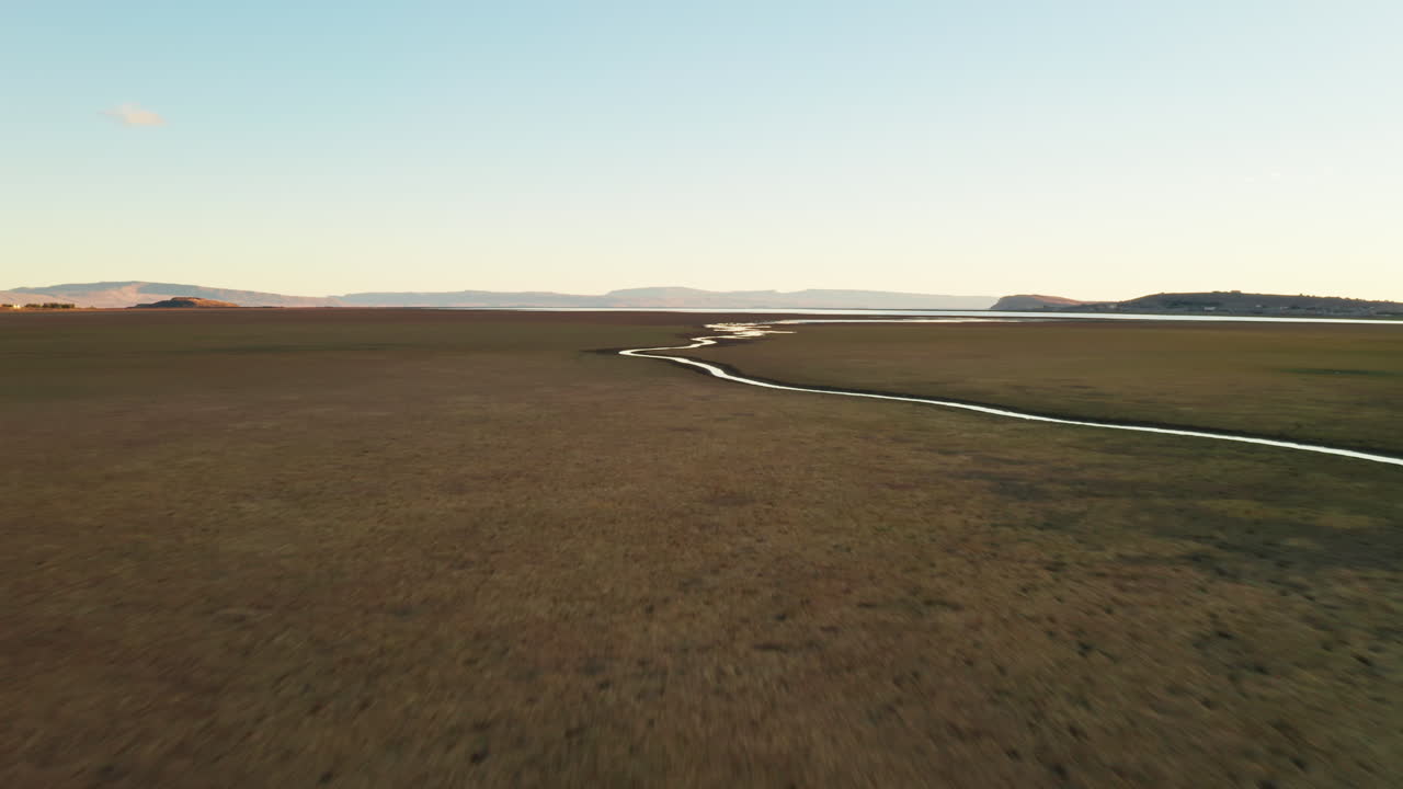Flying Low over Small Creek in the Patagonian Steppe.Aerial View of Brown Meadow Filed and Small Water Stream