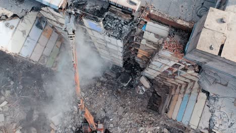 aerial view of excavator at a construction site destroys an old multi-storey building