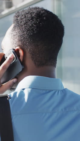 video de la vista de atrás de un hombre afroamericano caminando y usando un teléfono inteligente