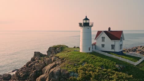 an aerial rotating view of nubble lighthouse in york beach, maine, captures the iconic landmark bathed in soft morning light