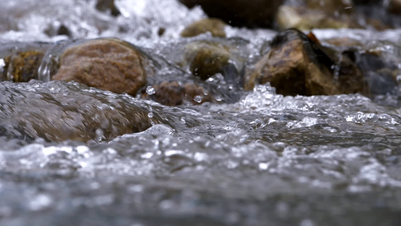 Clear stream running through stone boulders Abundant river flowing in slow motion