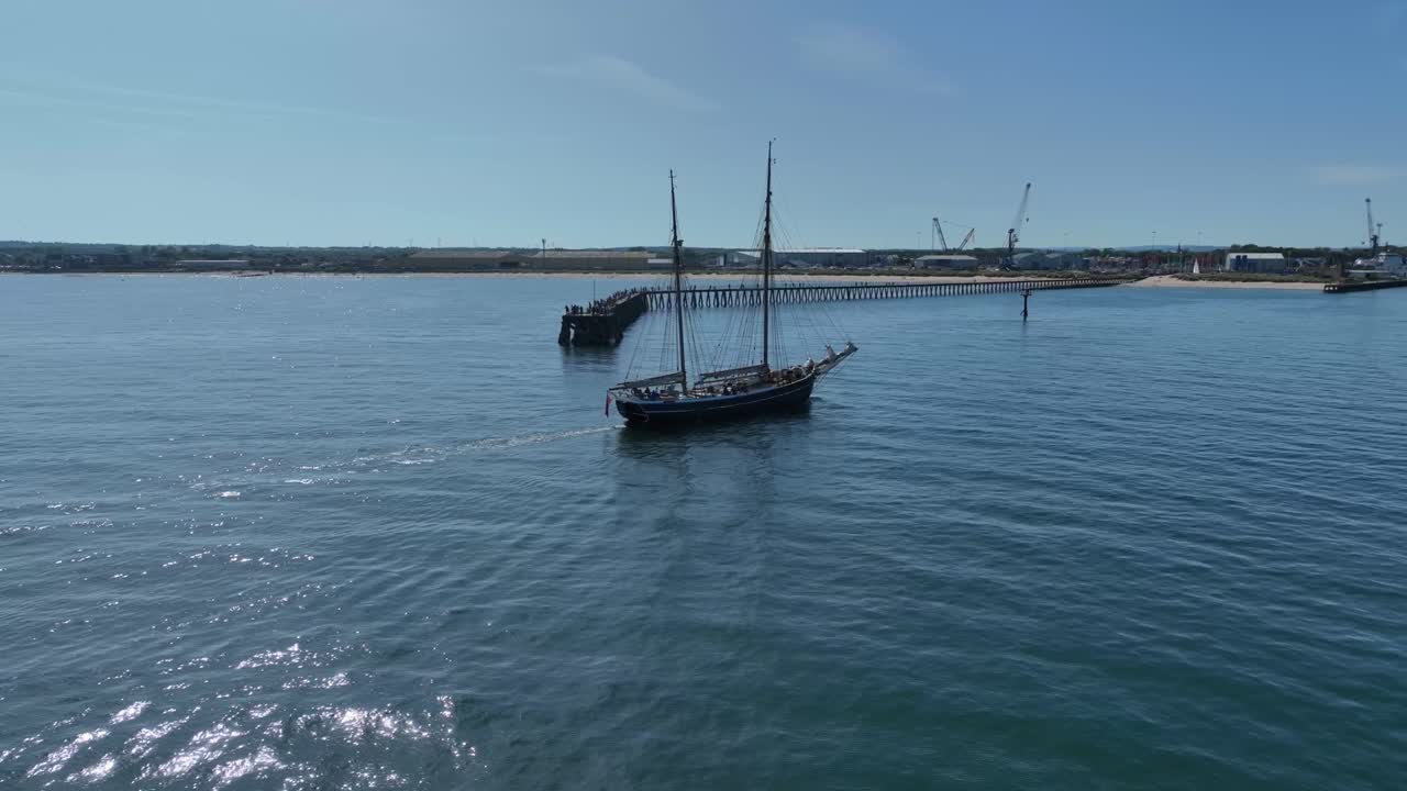 Aerial clip showing tall ship entering Blyth harbour in Northumberland, England on a sunny summer day