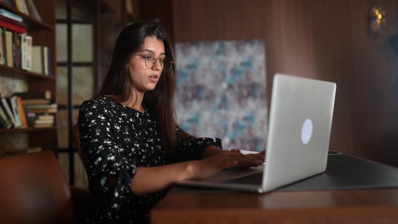 mujer trabajando en una computadora portátil en una biblioteca