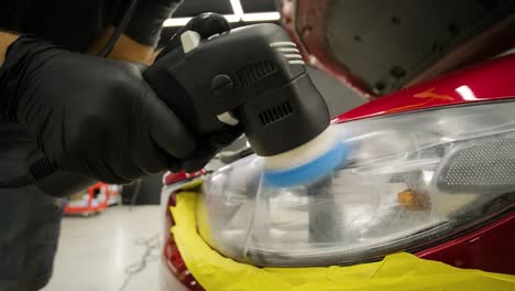 headlight polishing, processing of car lights. a car service worker polishes the headlight of a passenger car. professional polishing.