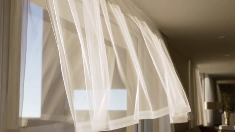 white sheer curtains blowing gently in the breeze by a window