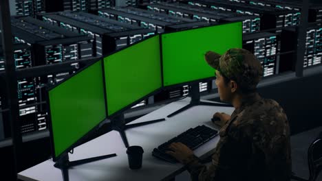 vista lateral de militares asiáticos pensando en algo mientras trabajan con simulacro de múltiples monitores de computadora en el centro de datos