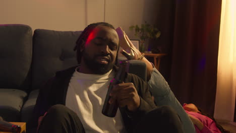 man sitting by sofa at house party deciding he has had enough alcohol to drink 2