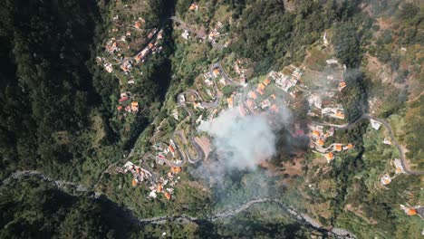 Fuego-Y-Humo-En-Un-Pequeño-Pueblo-En-Un-Valle-Verde-En-Madeira,-Bosque-Verde,-Paisaje,-Portugal,-Drone,-Aéreo