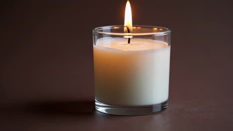 a lit candle in a glass holder