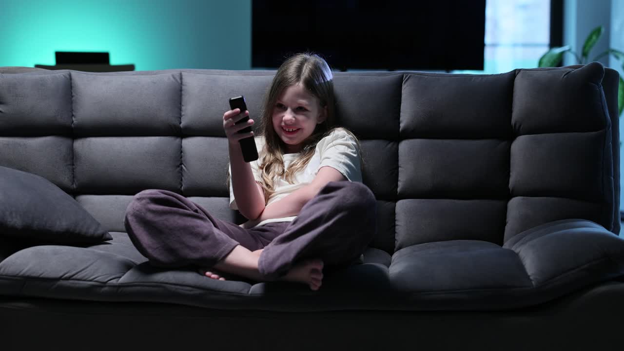 Pige, der ser fjernsyn på sofaen