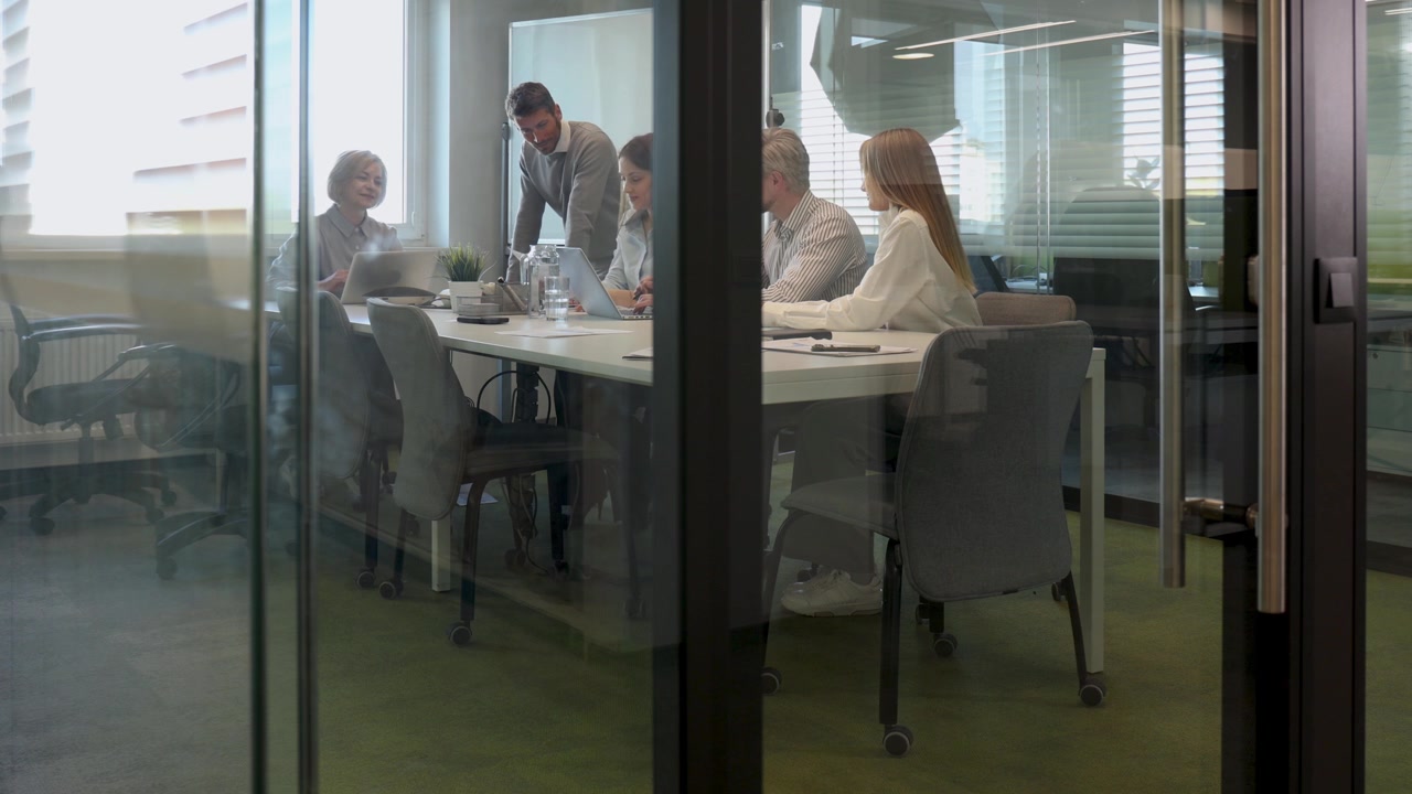 Squadra professionale che collabora in una moderna sala riunioni con pareti in vetro.