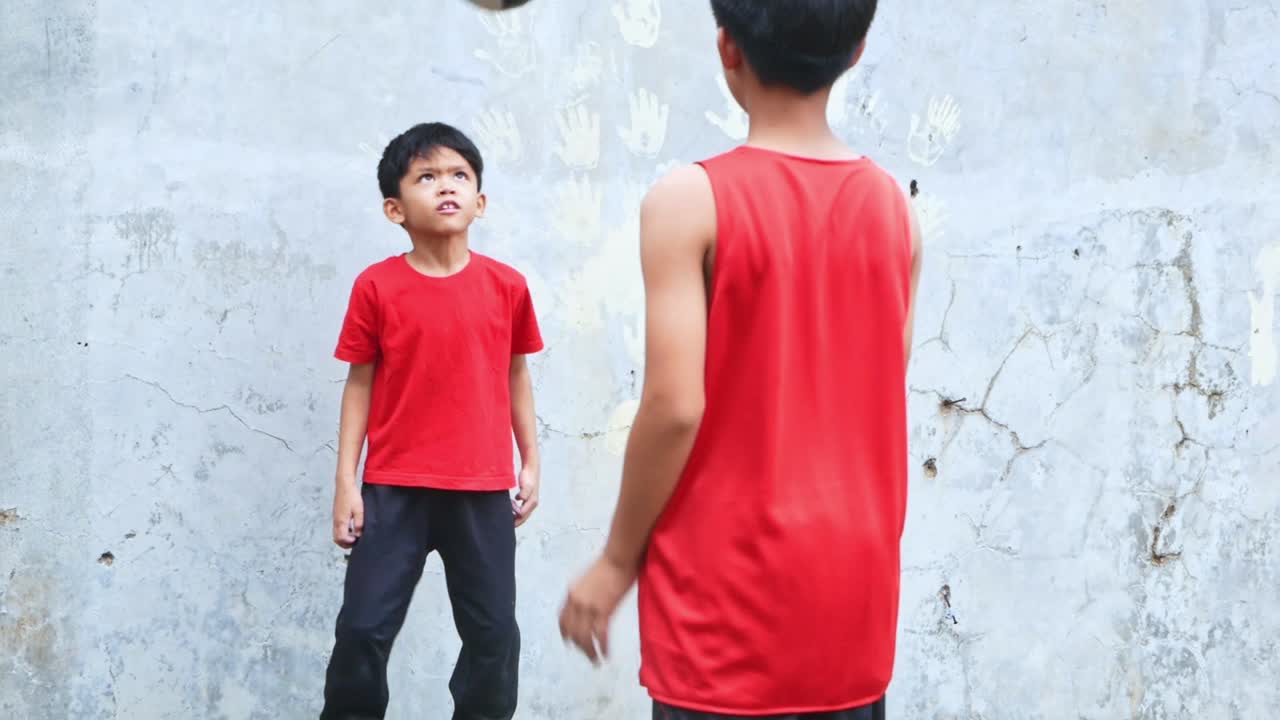 Young asian boys and brother practicing soccer skills heading ball outdoor