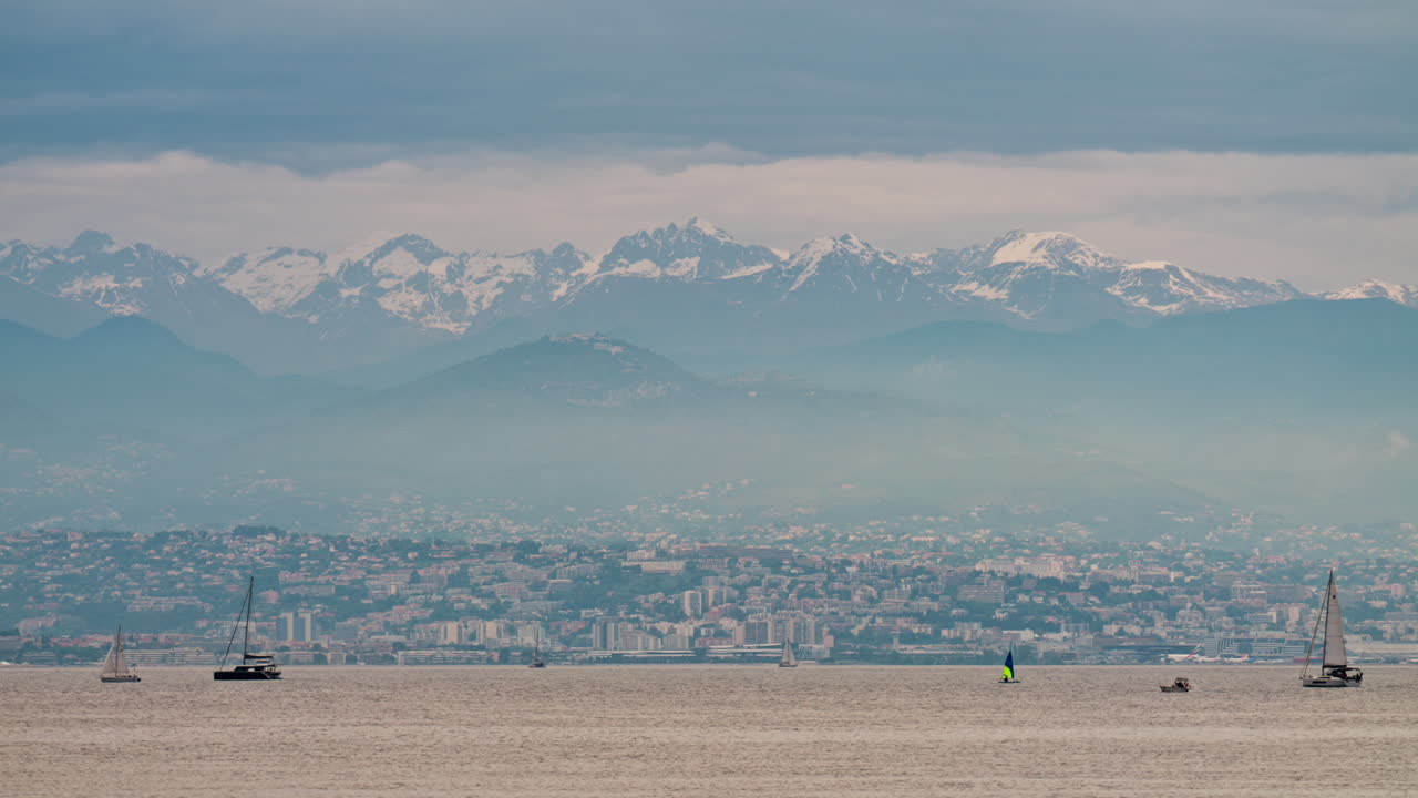 Antibes, France - May 6, 2025: Distant view of multiple boats moving on the sea with the city and the mountains on the background