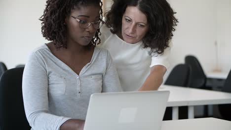 Two-focused-workers-talking-and-looking-at-laptop.