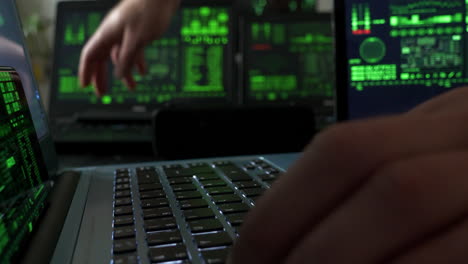 Close-up-slide-shot-of-hands-typing-fast-on-laptop-by-other-screens