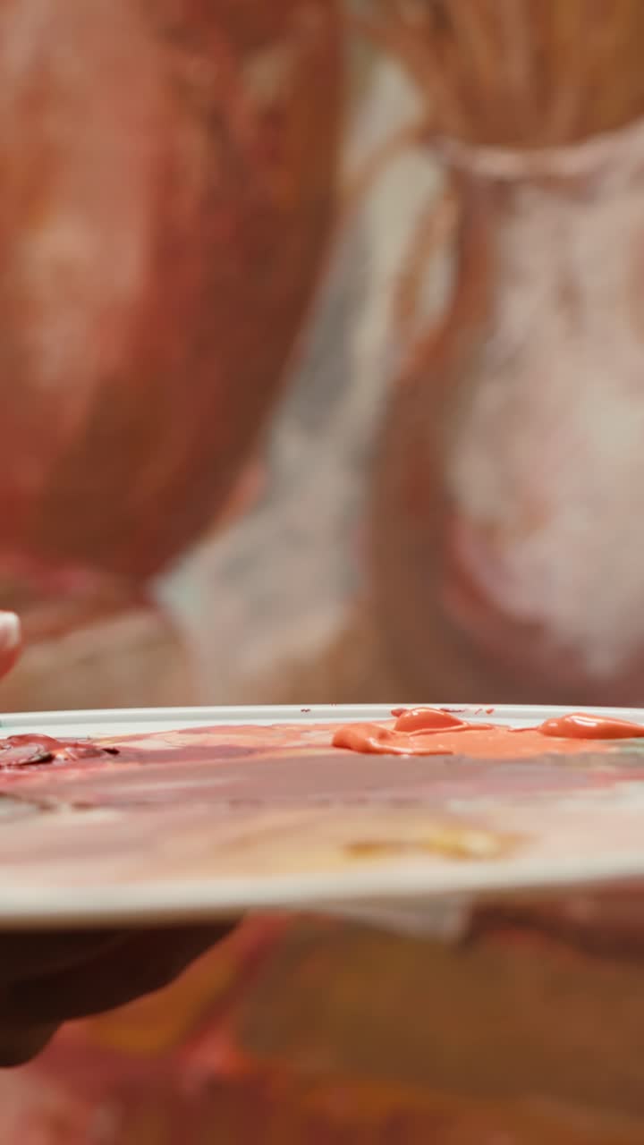 Artist's Hand Mixing Paint on Palette and Painting Canvas