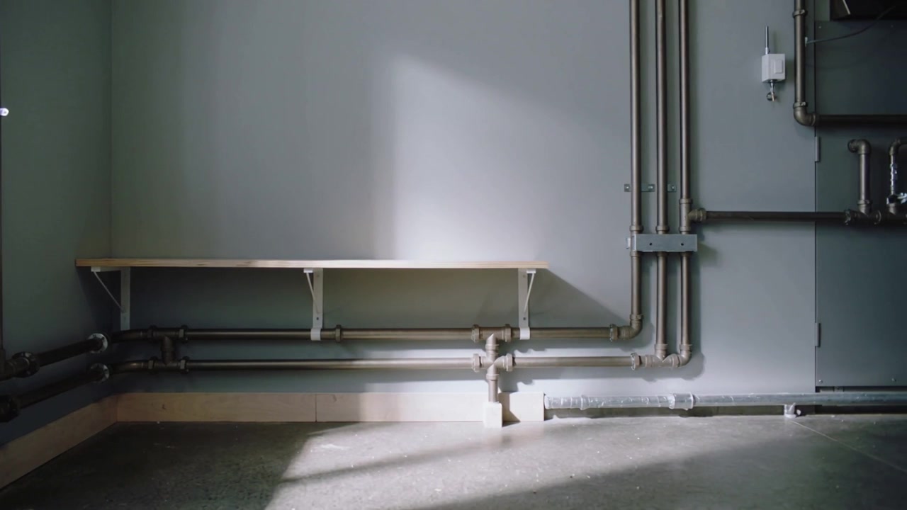 Streaming sun through left window sweeping and shifting across wall shelf and pipes in utility room