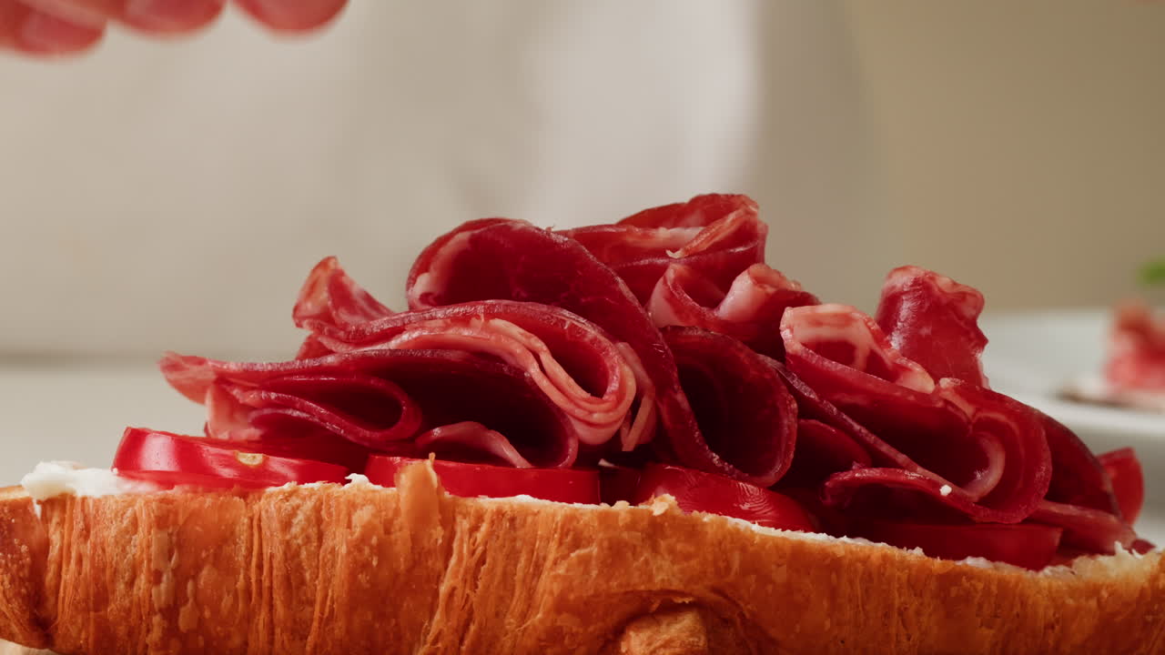 Preparing a Croissant Sandwich with Ham and Tomatoes