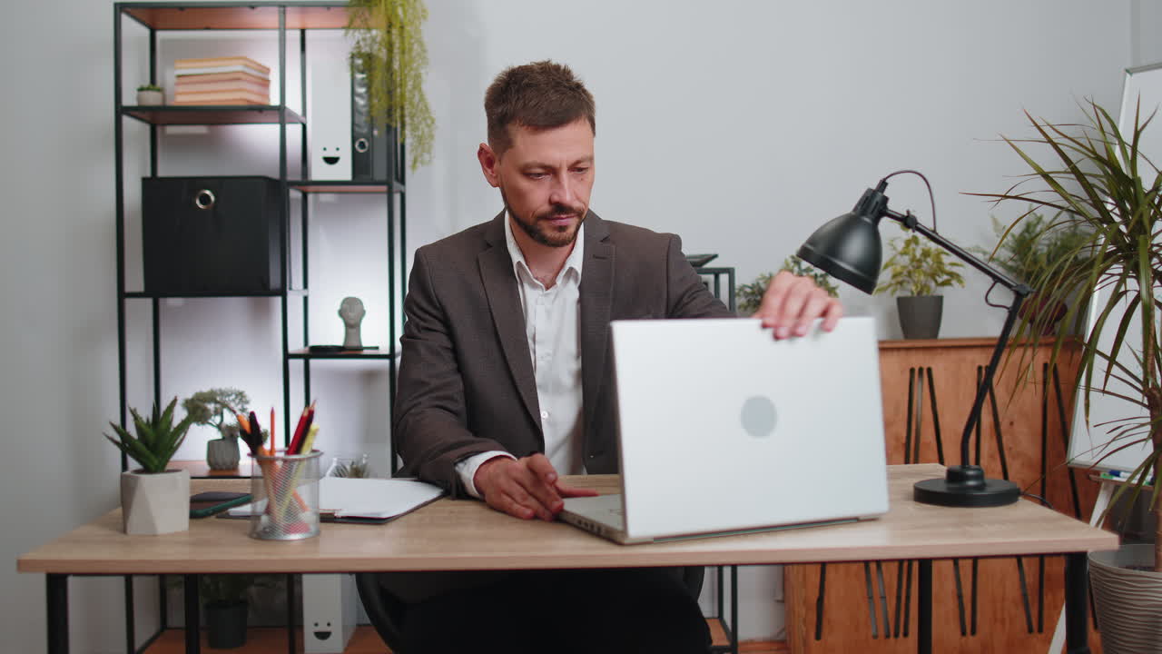 Uomo d'affari freelance entra in ufficio, lavora al laptop e invia messaggi online.