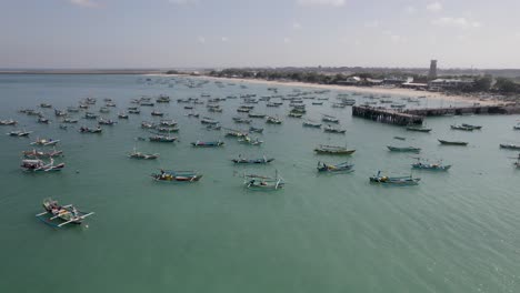 aerial view of indonesian traditional juking boats bobing near the pier on turquoise transparent waves near a tropical island of bali