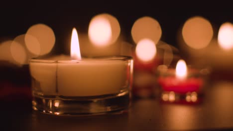 Close-Up-Of-Romantic-Lit-Red-And-White-Candles-Burning-On-Black-Background-With-Bokeh-Lighting