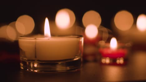 primer plano de velas rojas y blancas iluminadas románticamente ardiendo sobre un fondo negro con iluminación bokeh