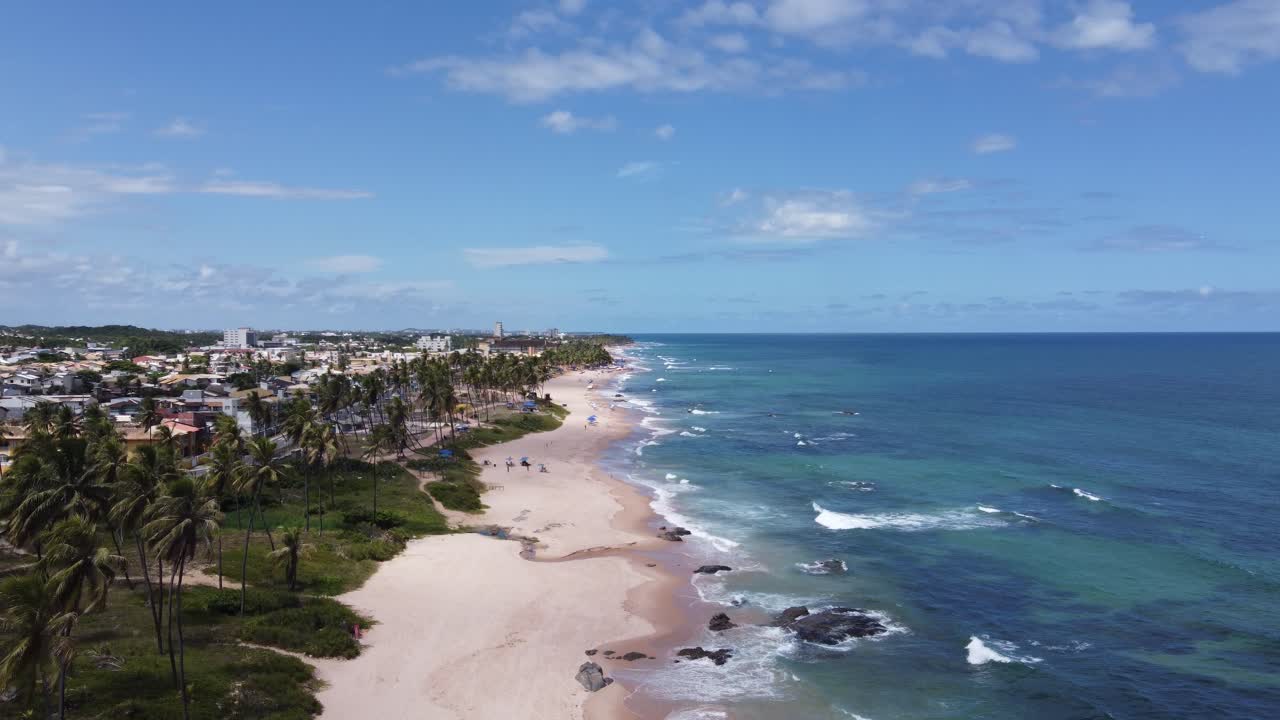 A breathtaking drone shot moving up and forward, revealing a beautiful beach in Salvador, Bahia, Brazil, with golden sand and turquoise waters on a sunny day