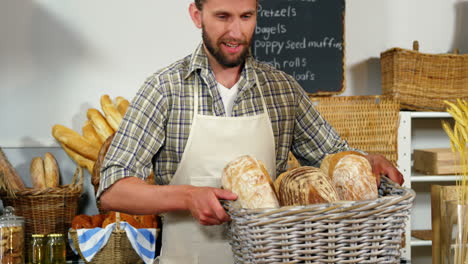 portrait of male staff holding breads in basket at bakery section