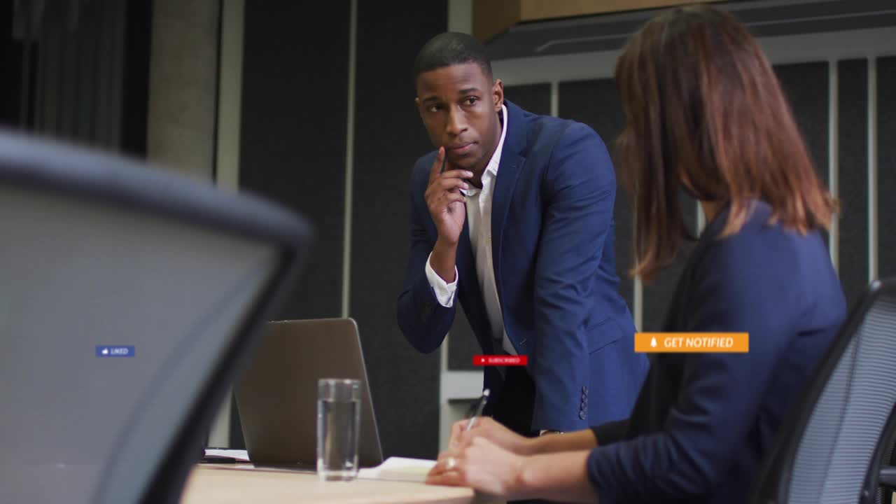 Man gesturing at laptop causing social badges growing then settling, woman writing for marketing
