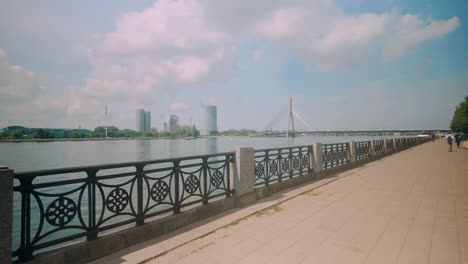 footage of riga's riverbanks along the daugava river, showcasing a view of a bridge and the high-rise financial district under a clear sky