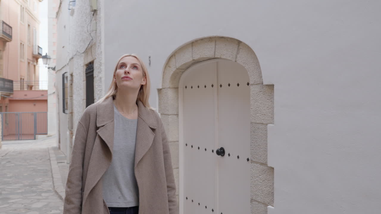 Tourist woman walking down a white stone building street, old town European architecture