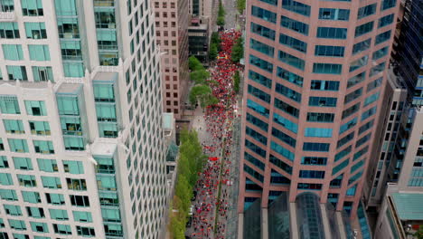 people in orange shirts fill the street to protest, high drone shot moving forward