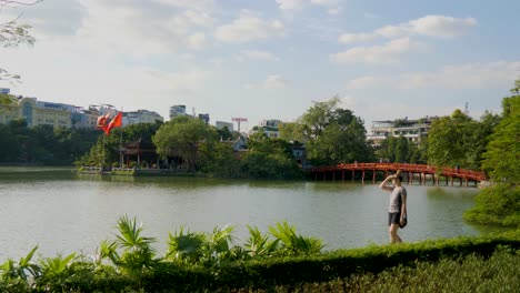 with vietnamese flags waving a young woman walking at hoan kiem lake