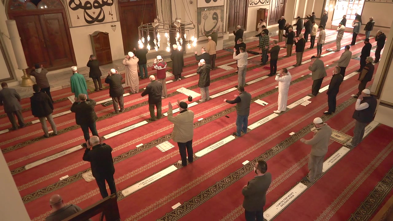 Uomini musulmani che pregano in moschea con distanziamento sociale.