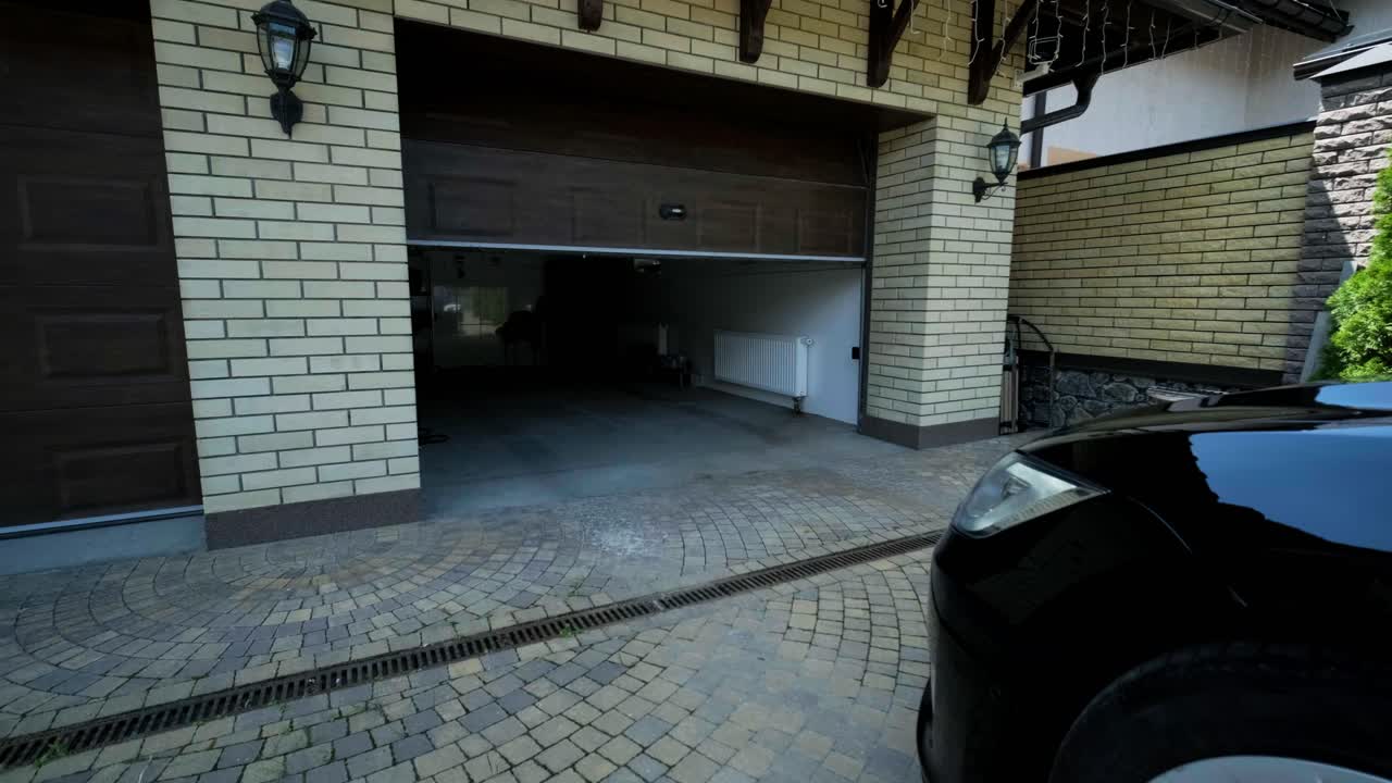 Man driver in car thumbed remote control to open the garage door in the house