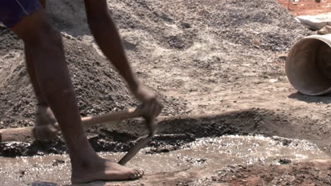 closeup of man making concrete in a pit with a shovel - manual labour