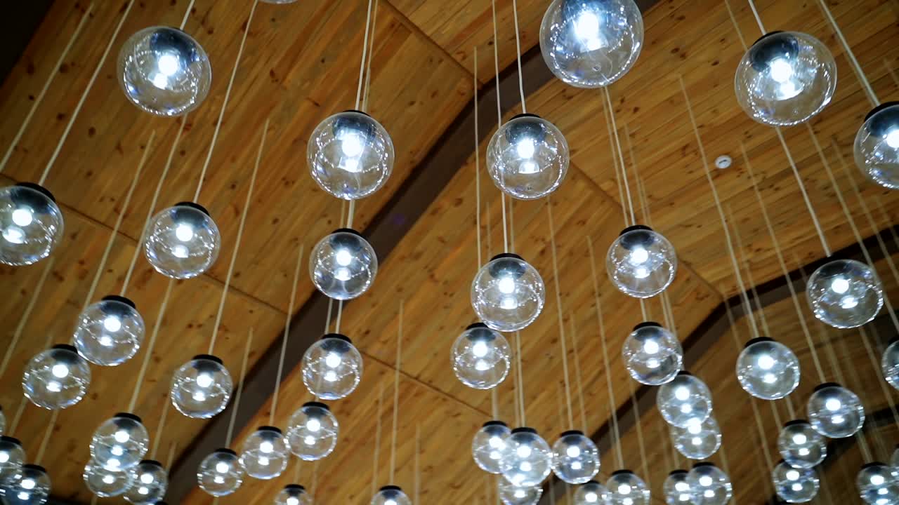Crystal balls hanging from brown ceiling. Beautiful ceiling with round glass light bulbs. Motion camera around.