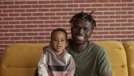 Mixed-race-family-dad-child-boy-happy-faces-sit-on-sofa-bonding,-closeup-portrait