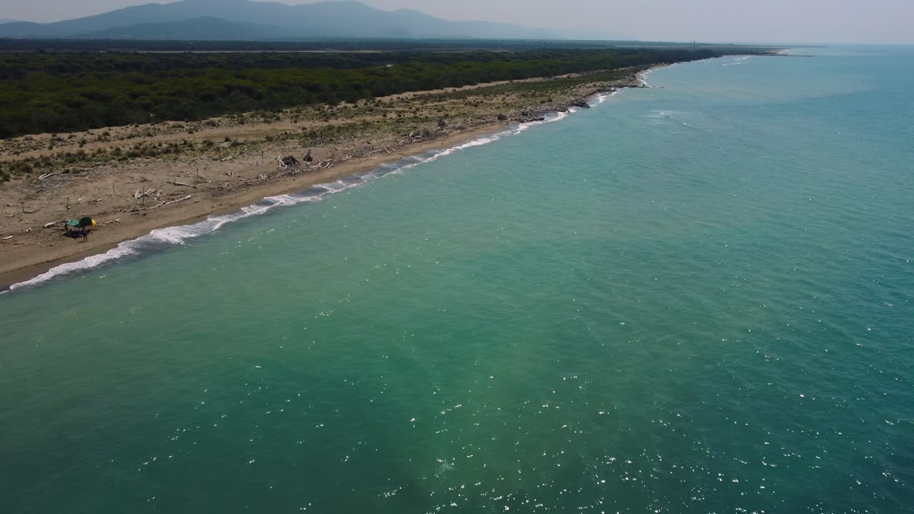 volando hacia una playa de arena al atardecer en la costa cerca de castiglione en el icónico parque natural maremma en toscana, italia, con olas, bosques de pinos y montañas