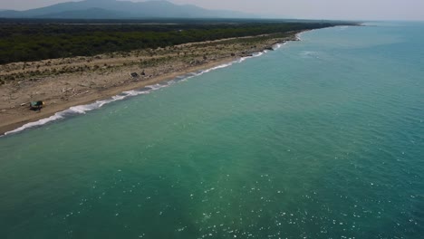 Volando-Hacia-Una-Playa-De-Arena-Al-Atardecer-En-La-Costa-Cerca-De-Castiglione-En-El-Icónico-Parque-Natural-Maremma-En-Toscana,-Italia,-Con-Olas,-Bosques-De-Pinos-Y-Montañas