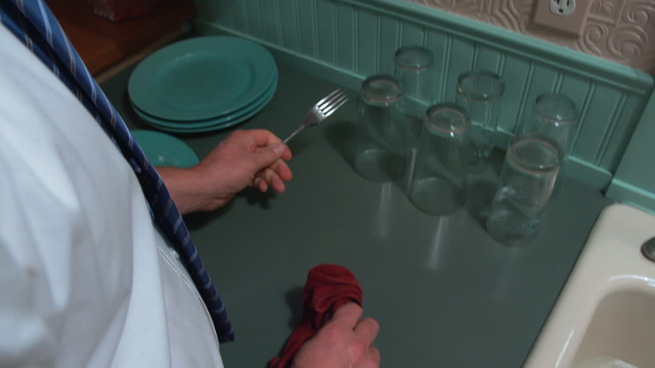 un par de manos lavando los platos y entregando un tenedor a otra persona