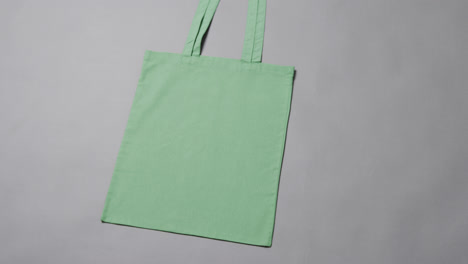 Primer-Plano-De-Una-Bolsa-Verde-Sobre-Fondo-Gris,-Con-Espacio-Para-Copiar,-Cámara-Lenta