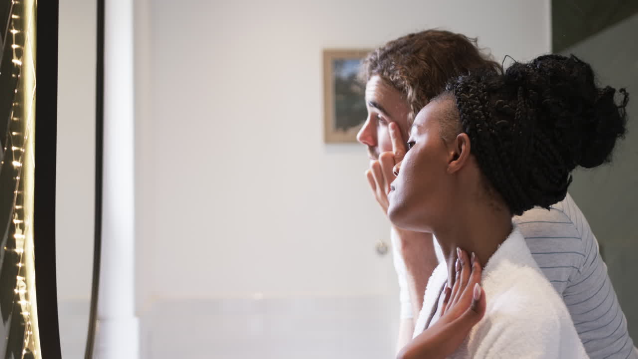 pareja diversa, un joven hombre caucásico y una mujer afroamericana, en un baño, con espacio de copia